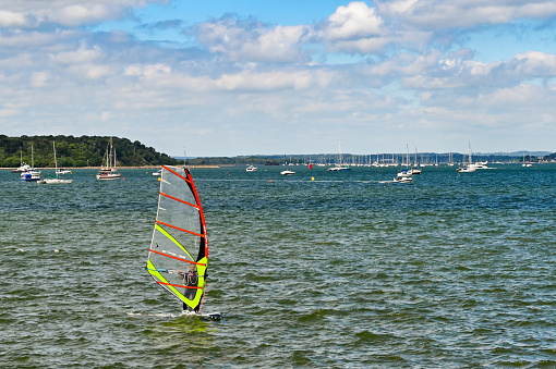 Poole, England - June 2021: Person windsurfing on choppy water in Poole harbour.