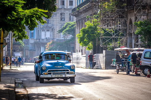 August 1, 2018 - La Havana, Cuba: blue old american classic car taxi and Bikes and bici-taxi in La Havana streets