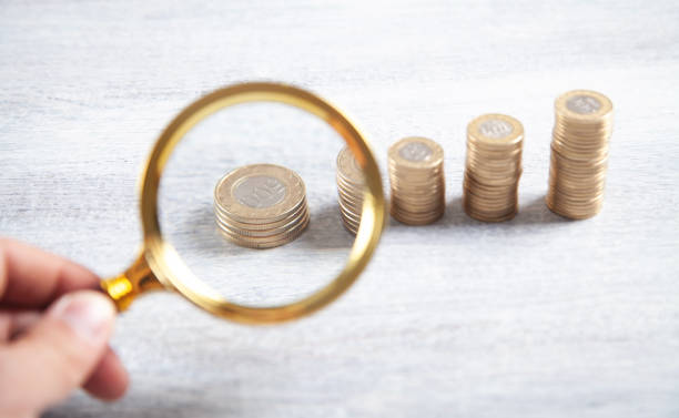 istock Male hand magnifying coins. Inspect income 1327152139