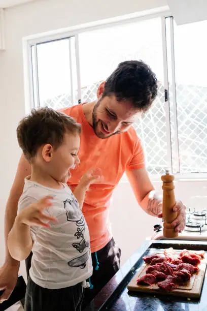 Father and son cooking meat