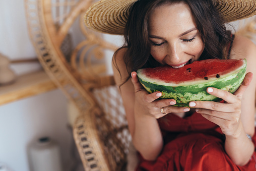 Young woman eats a large piece of watermelon.