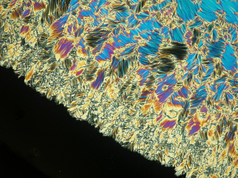 Forming Liquid crystal in its liquid crystal state under polarized light microscope creating a colorful texture. Abstract crystal background.