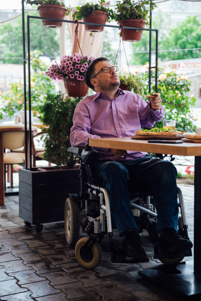 istock Disabled man with wheelchair in restaurant eats pizza 1327158954