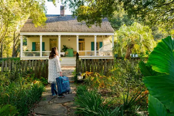 Female guest arrives to stay at Maison Madeleine, a restored 1840'2 French Creole cottage on the edge of Lake Martin swamp, Lafayette, Breaux Bridge, Louisiana