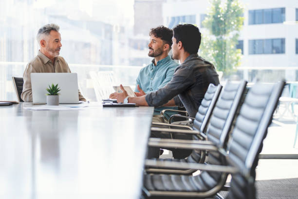 istock Three businessmen meeting at a board room table. 1327161153