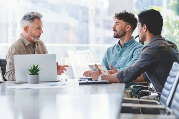 istock Three businessmen meeting at a board room table. 1327161154