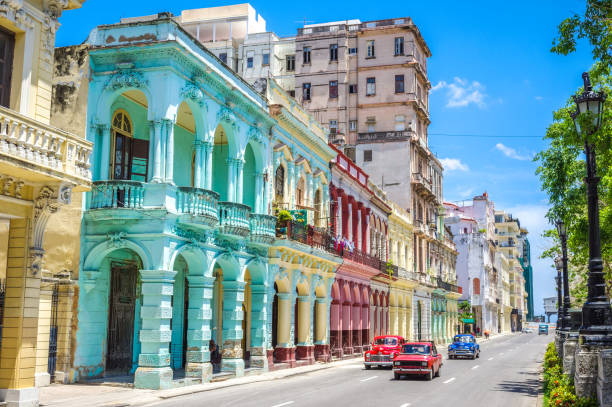 vecchie auto d'epoca americane multicolori in strada all'avana contro edifici storici - havana foto e immagini stock