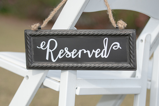 Reseved seating sign on white chair at outdoor wedding ceremony