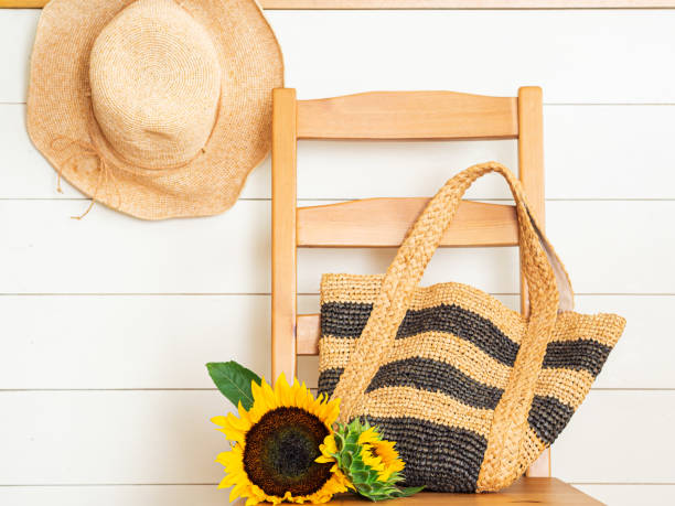 Summer hat,bag and sunflower on chair Summer hat,bag and sunflower on chair raffia stock pictures, royalty-free photos & images