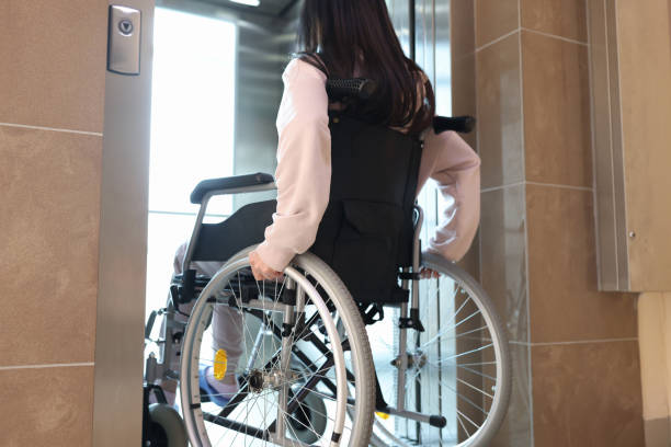 istock Disabled woman in wheelchair entering elevator back view 1327181370