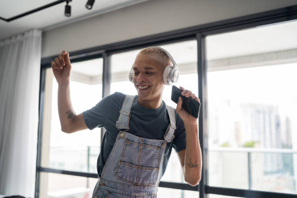 un jeune homme excité chantant et dansant à la maison - men smiling headphones individuality photos et images de collection