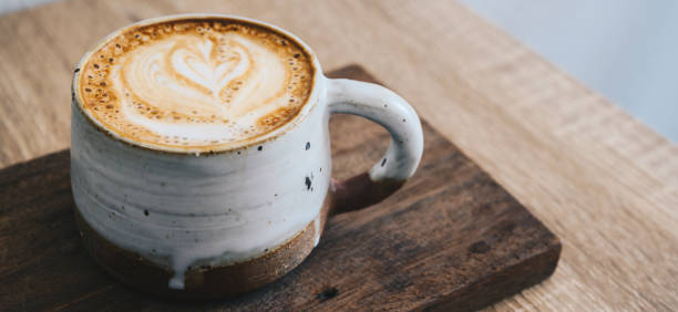 A cup of hot latte coffee on wooden table.