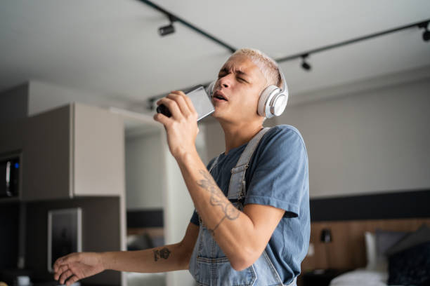 joven cantando y bailando en casa - cantar fotografías e imágenes de stock