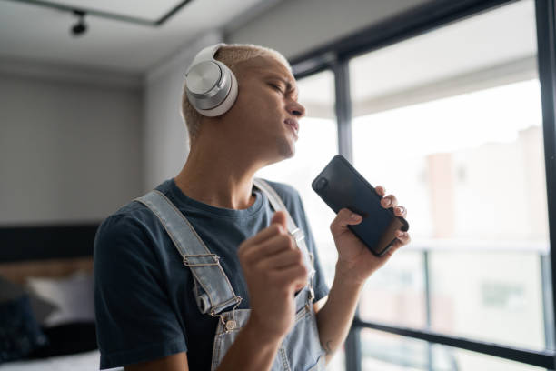 istock Young man singing and dancing at home 1327182448
