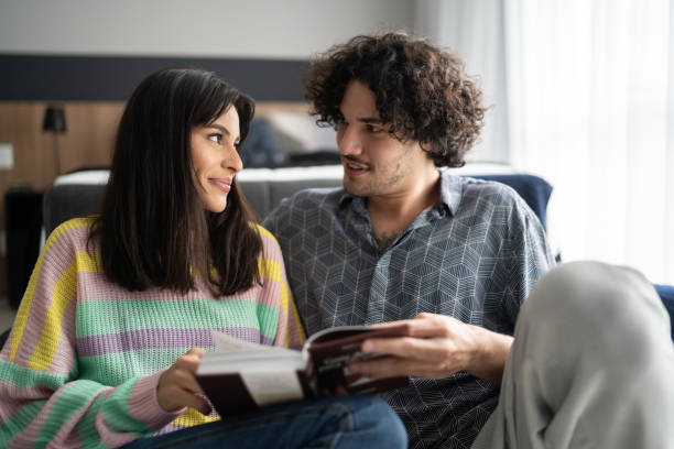 istock Young couple reading book together at home 1327182455