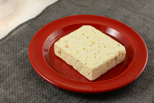 Tomato and basil feta cheese block Block of tomato and basil feta cheese on red plate on gray burlap table runner feta cheese block stock pictures, royalty-free photos & images