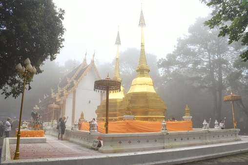 Chiang Rai, THAILAND - 12 August 2018 : Two golden pagoda at Phra That Doi Tung temple on a foggy day, Chiang Rai, Thailand. This place is a public domain or treasure of Buddhism.