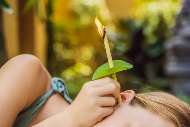 Ear candling being carried out on an attractive caucasian woman in a spa.
