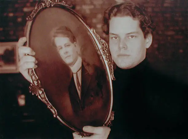 A young man holds a portrait of his grandfather taken in 1910.