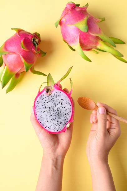istock Dragon fruit holding by hand and eating on yellow background 1327194588