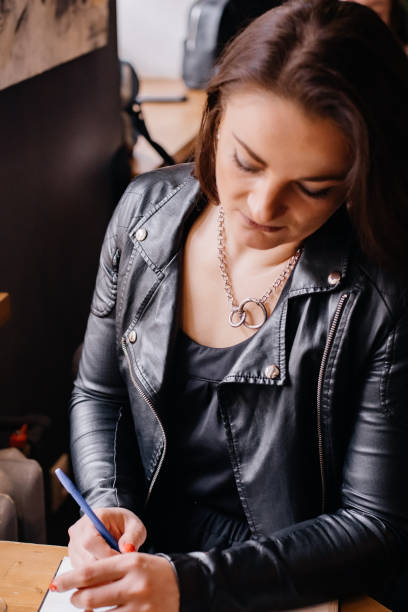 istock A woman is sitting at a table in a cafe, writing something down in a notebook. 1327196718