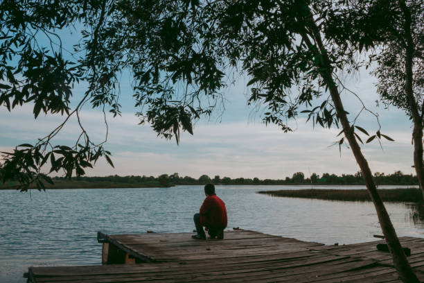 Young man relaxing sitting by the lake, Seran Lake Banjarbaru, Indonesia