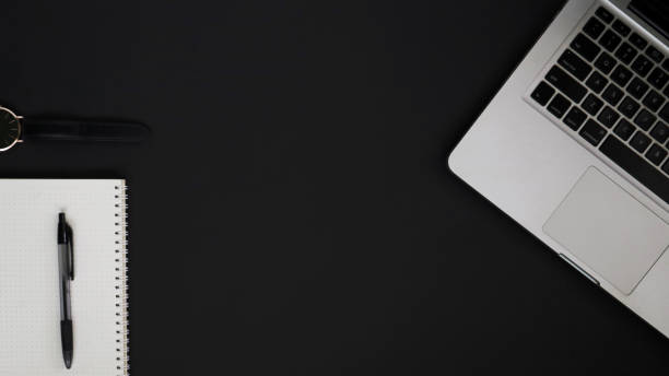 istock Top view of work desk on black background 1327203321
