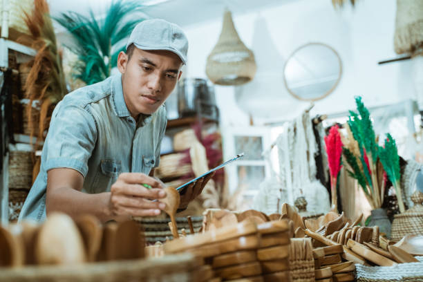 man holds a craft item and clipboard while checking items among craft items - fake rattan imagens e fotografias de stock