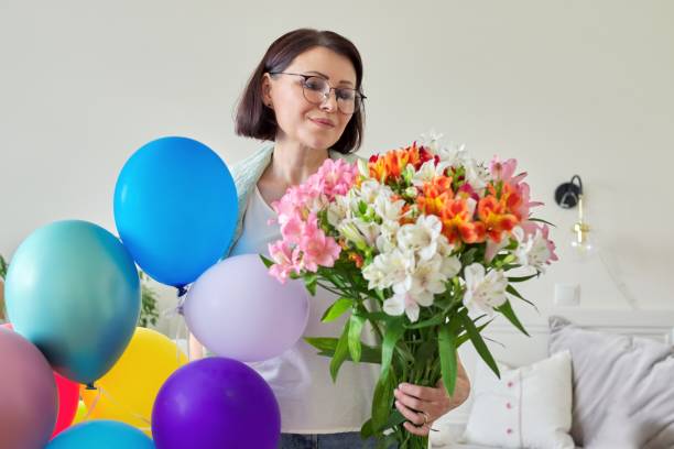 compleanno, 45 anni, donna felice con bouquet di fiori e palloncini - 40 45 years immagine foto e immagini stock