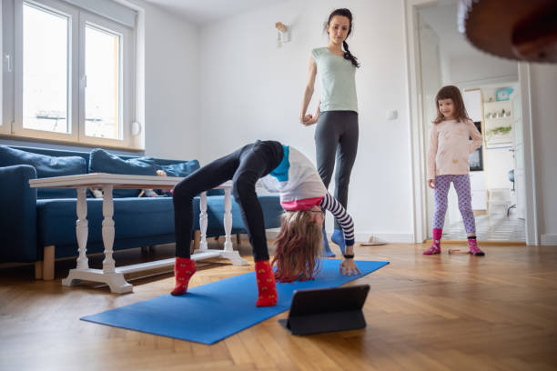istock Girl having fun with mother and sister, doing acrobatic postures on exercise mat 1327209965