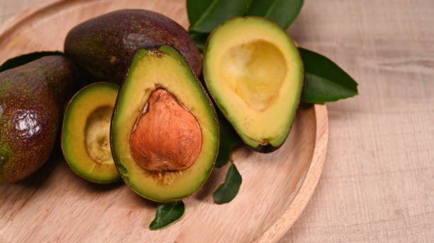 istock Close up whole avocado and half with seed on wooden plate. 1327212301