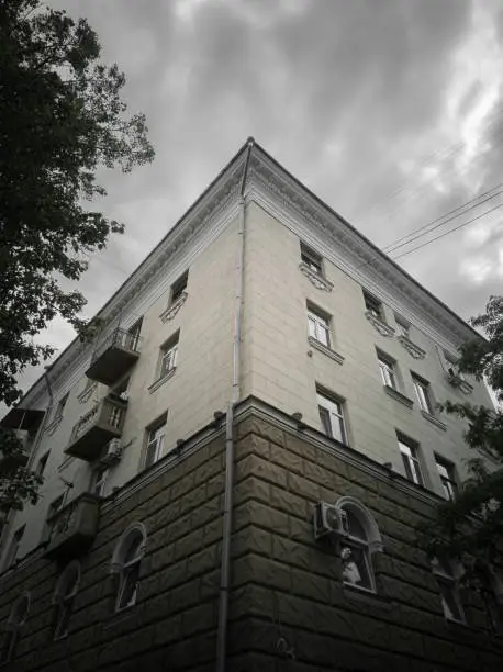 Fragment of the classicism facade of the house on a cloudy day. House in the style of the Stalinist Empire, bottom-up view.