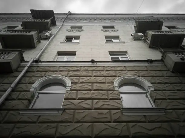 Fragment of the classicism facade of the house on a cloudy day. House in the style of the Stalinist Empire, bottom-up view.