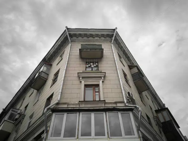 Fragment of the classicism facade of the house on the corner on a cloudy day. House in the style of the Stalinist Empire, bottom-up view.