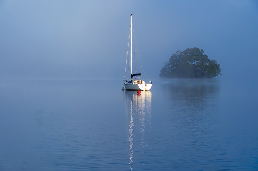 A yacht on a misty Lake Windermere in the English Lake District.