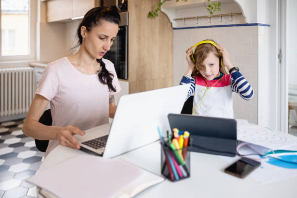 istock Mother working on laptop from home, her daughter attending online class on tablet 1327217295