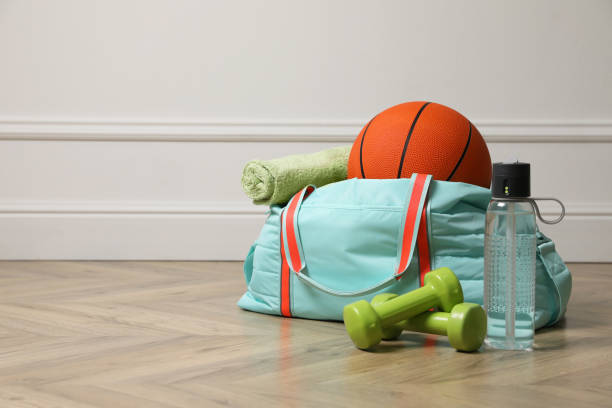 Blue gym bag with sports accessories on floor near white wall indoors, space for text Blue gym bag with sports accessories on floor near white wall indoors, space for text sports equipment stock pictures, royalty-free photos & images
