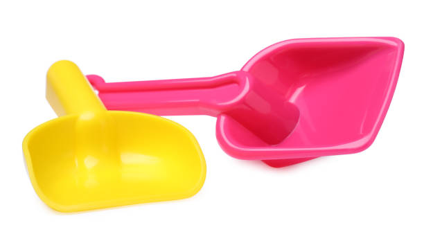 istock Yellow and pink plastic toy shovels on white background 1327221751