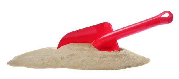 Pile of sand and red plastic toy shovel on white background