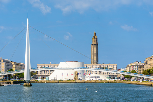 Le Havre, France - June 9, 2021: The Volcan cultural center and the Oscar Niemeyer public library with the footbridge of the Commerce basin in the foreground and the bell tower of St. Joseph's Church.