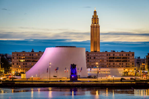 The Volcan theater and St. Joseph's Church at nightfall in Le Havre, France. Le Havre, France - June 9, 2021: The Volcan cultural center and the Oscar Niemeyer public library with the war memorial in the foreground and the bell tower of St. Joseph's Church at nightfall. normandy photos stock pictures, royalty-free photos & images