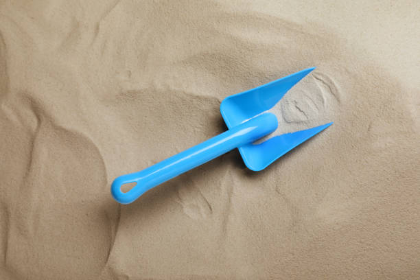 Bright plastic toy shovel on sand, top view