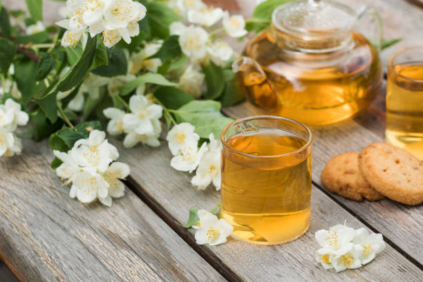 thé chinois vert avec jasmin dans des tasses et une théière sur un plateau de table en bois avec un bouquet de fleurs de jasmin. - tea green tea jasmine chinese tea photos et images de collection