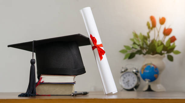 istock Mortar board with degree paper on wood table. graduation concept. 1327229196
