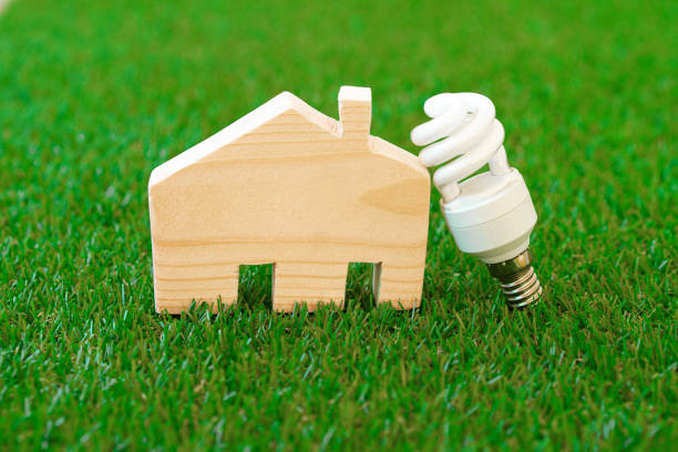 istock Wooden house model and lightbulb on green background 1327229253