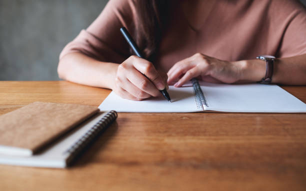 istock a woman writing on a blank notebook on wooden table 1327229301