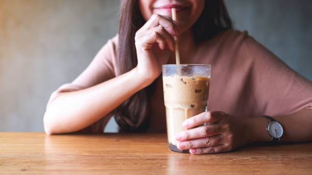 istock a young woman holding and drinking iced coffee 1327229331