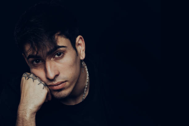 istock Young man with tattoos and earrings with a pensive expression 1327230051