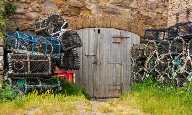 Piles of lobster creels stacked up on a pier outside the door to a storage shed