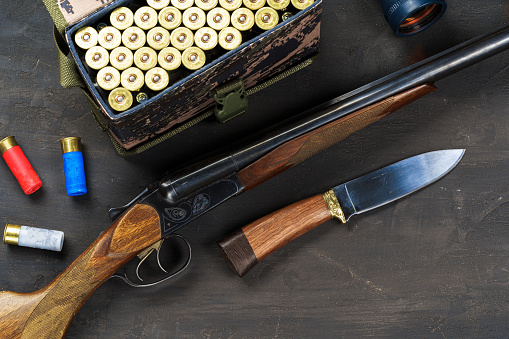 Hunting rifle and cartridges on dark wooden background, close up